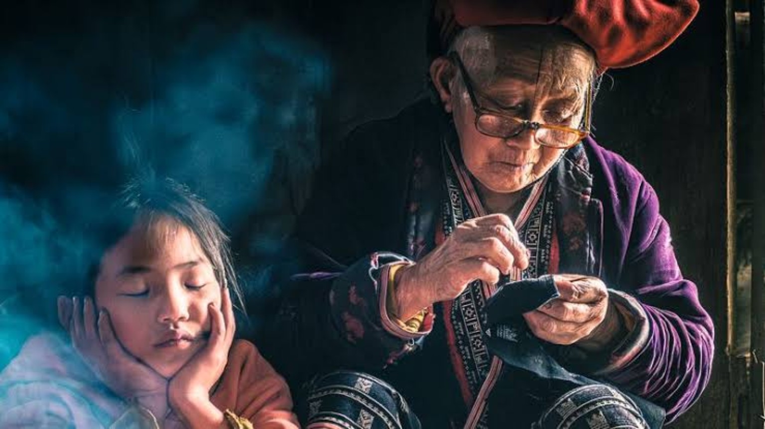 Older woman sewing beside a young child